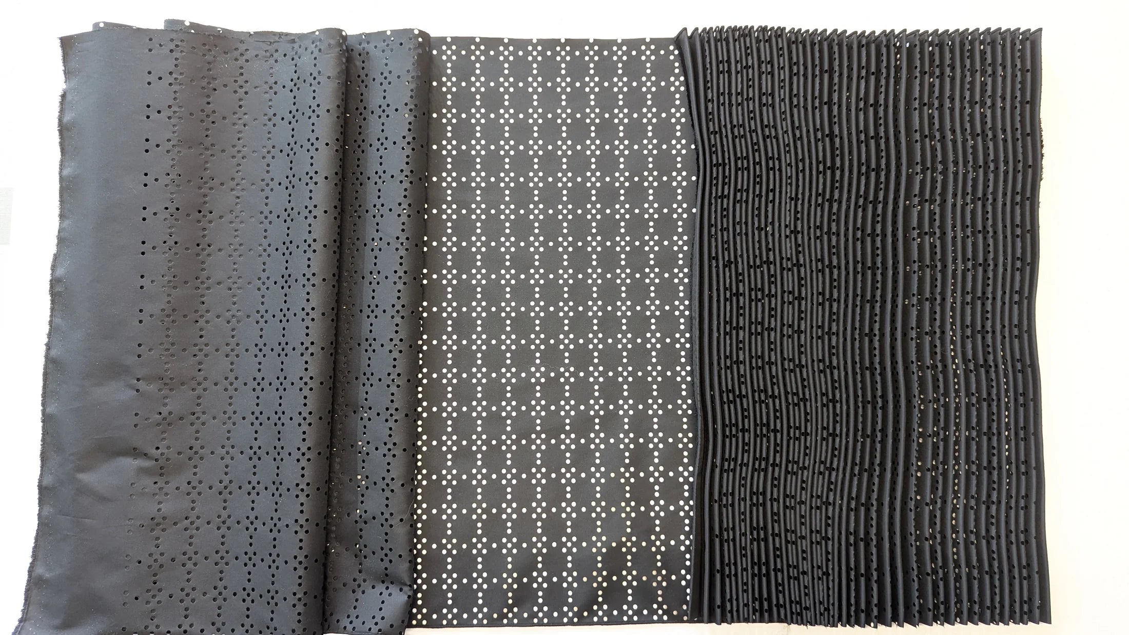 Perforated black fabric shown flat, partly formed and fully pleated